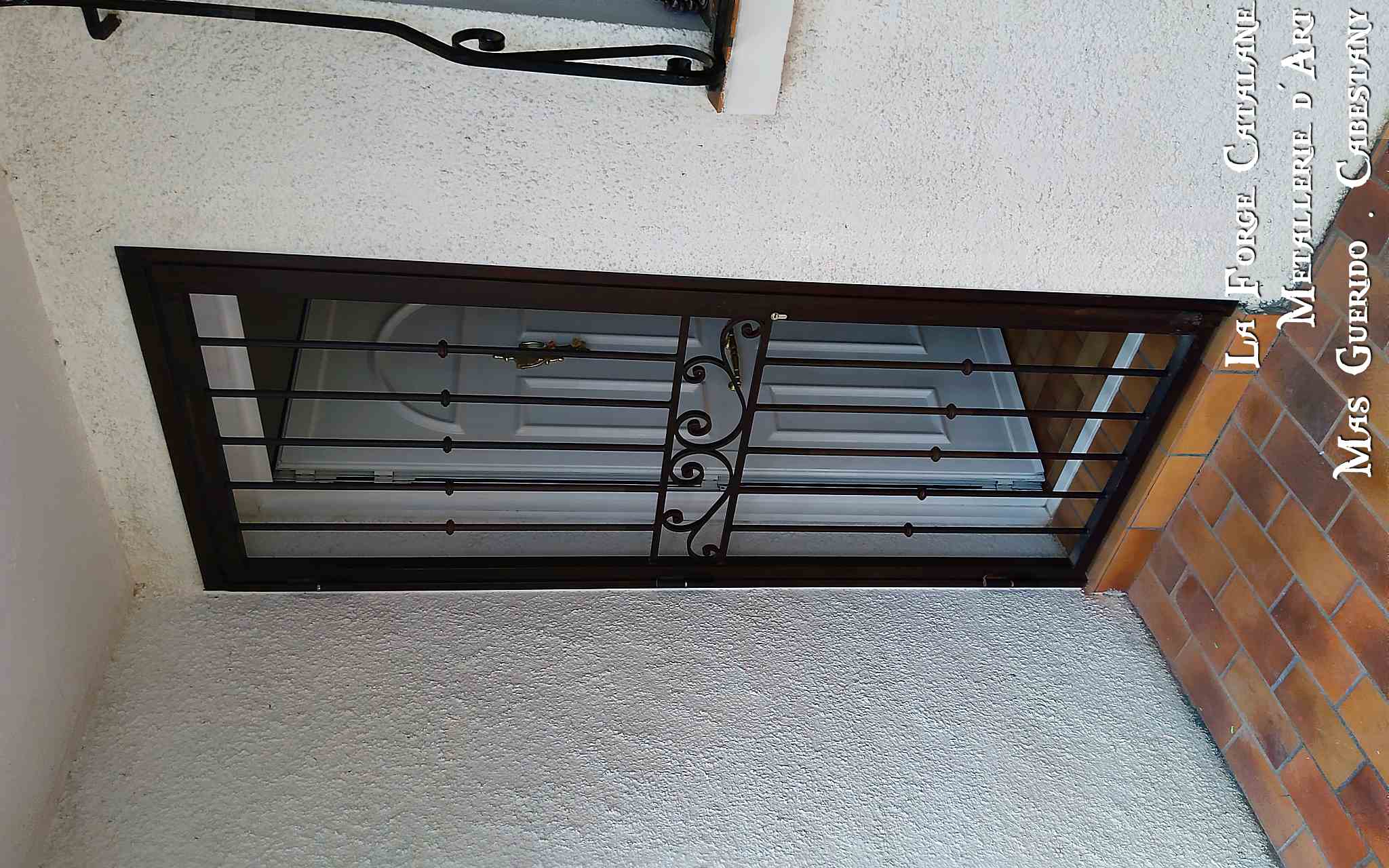 grille articulee devant porte rouille barreaux fer rond bagues frise volute la forge catalane.jpg